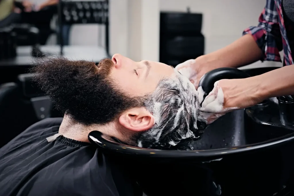 Hairdresser washing bearded men's hair.